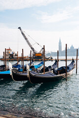 Fototapeta premium Gondolas docked at the waterfront in Venice near construction and towers