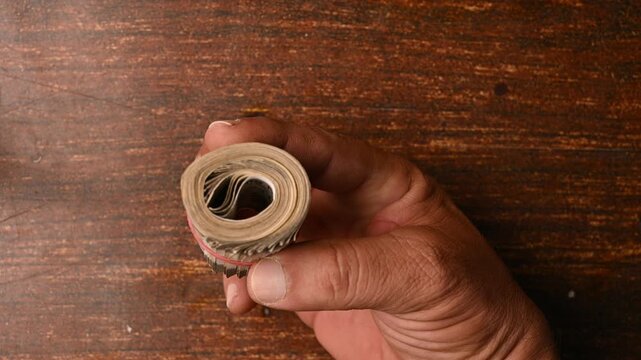 Top View of a Man Placing 500 Rupee Round Bundle on Wooden Table &ndash; Finance Footage