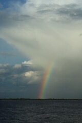 Vibrant rainbow and heavy rain under dramatic storm clouds