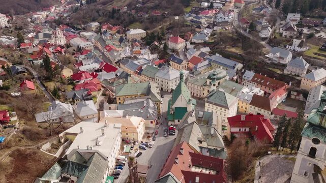 Wide aerial drone panorama of Banska Stiavnica, Slovakia. Historic old town, Holy Trinity Square, colorful rooftops and rolling hills in UNESCO heritage mining town.
