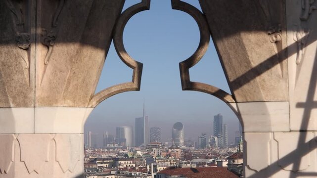 view of Milan's modern skyscrapers framed by the intricate gothic architectural details and spires of the Duomo di Milano cathedral in Italy
