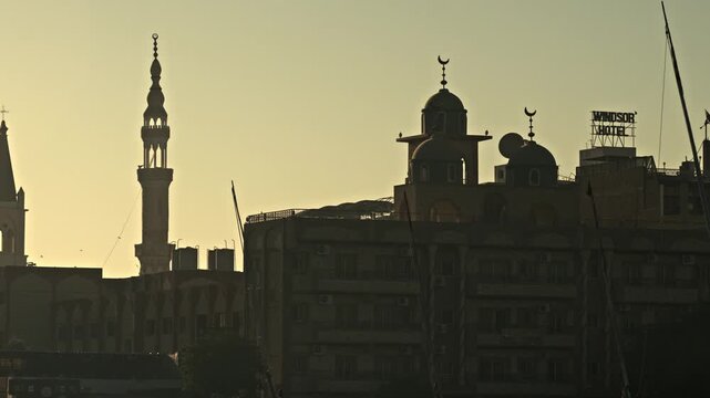 Located along the East Bank of the Nile in Luxor, Egypt, this sunset silhouette features the dual belfries of St. Mary's Coptic Orthodox Cathedral and Sheikh Hammami Mosque.