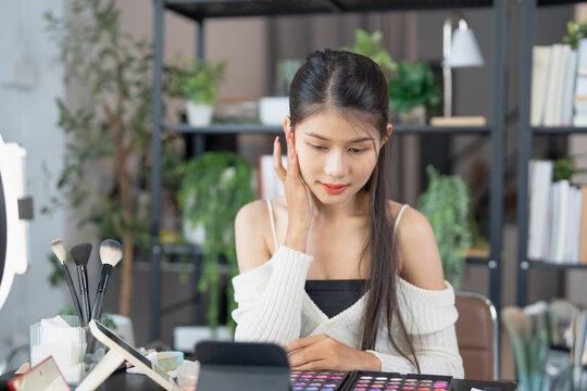 Asia woman beauty influencer makeup artist vlogger live streaming makeup tutorial on smartphone for social media