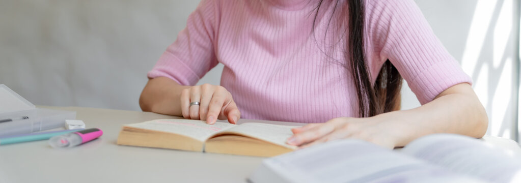 Asian girl&nbsp;student reading book preparing for college exam Young female student studying and writing on notebook making &nbsp;in school library