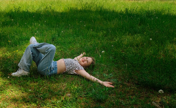 Adolescent girl having fun, enjoying lying on lawn. Wordless appreciation for nature. Freedom, carefree. Individuality, alternative lifestyle. Activity summer vacations. Lifestyle photography. Summer.