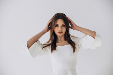 Naklejka premium Beauty portrait of a model, a beautiful brunette girl with straight long hair in a white dress, healthy and natural on a white background