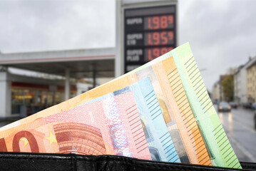 Euro Geldscheine und hohe Preise an einer Tankstelle wegen Inflation, Krise oder einem Krieg