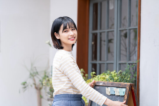 お店の前で看板を出している女性