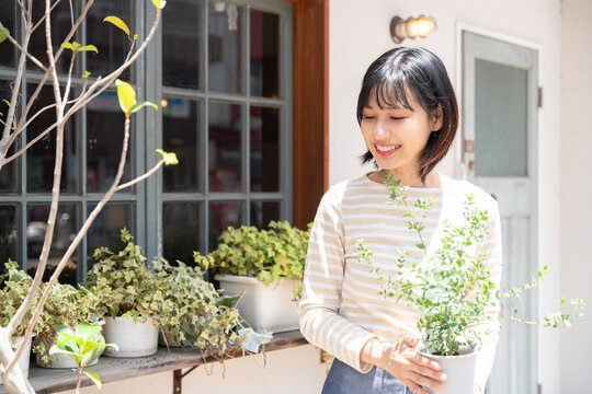 お店の前で鉢植えを持っている女性