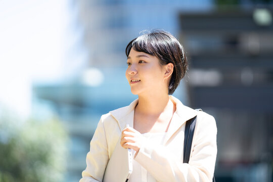 パソコンを抱えて外を歩いている女性