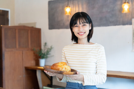 お店でパンを持って笑っている女性