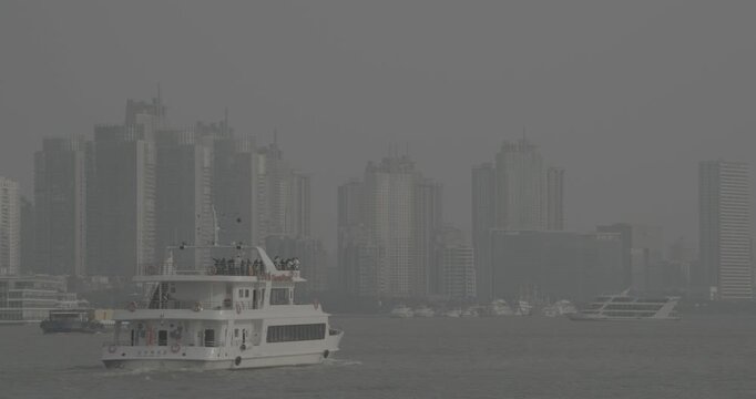 River cruise boat navigating through bustling cityscape with skyscrapers in view. Shanghai, China