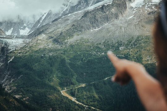 Hand pointing toward a distant glacier in the mountains