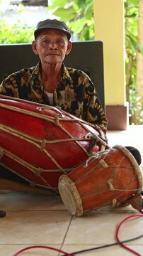 Elderly Indonesian musician playing traditional kendang drum