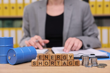 A professional figure in a grey suit analyzes data, surrounded by stacks of documents, oil barrels,...