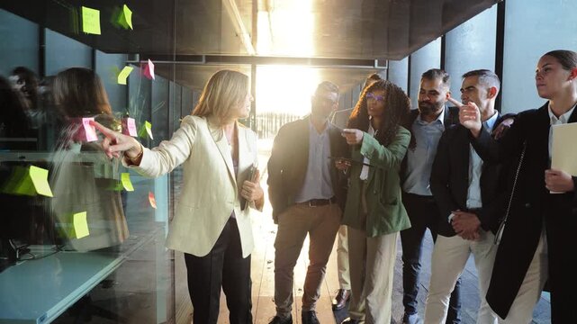 A group of enthusiastic professionals actively participating in a productive brainstorming session, sharing insights and pointing at colorful sticky notes to enhance their collaborative efforts.