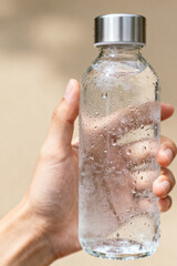 A bottle of cold water with drops in your hand