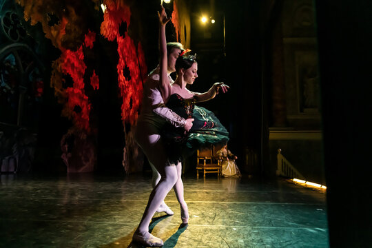 Woman and man performing ballet on theatrical stage.