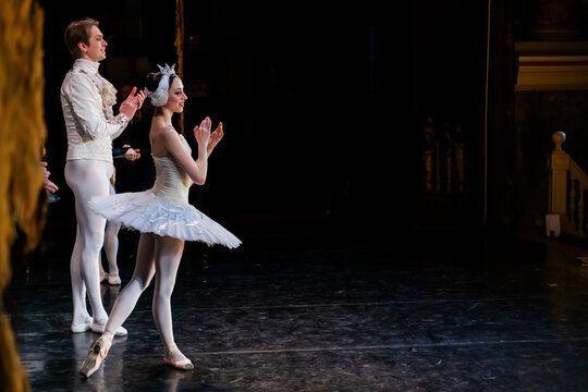 ballerina and man dancer on stage bowing and clapping.