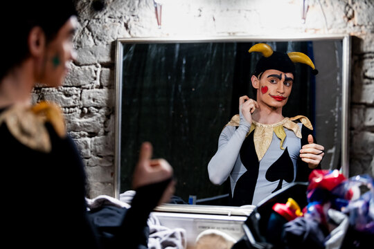 Man ballerino in jester costume reflecting in mirror in theater