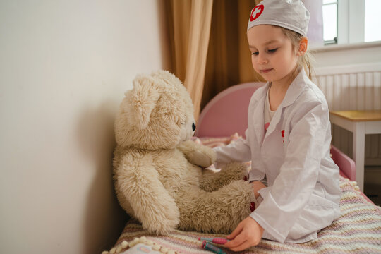 Little girl in doctor costume pretending to treat her toys