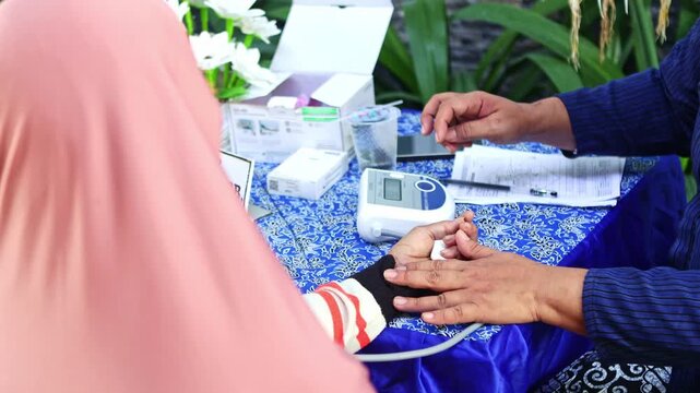 Nurse checking woman's blood pressure during health screening