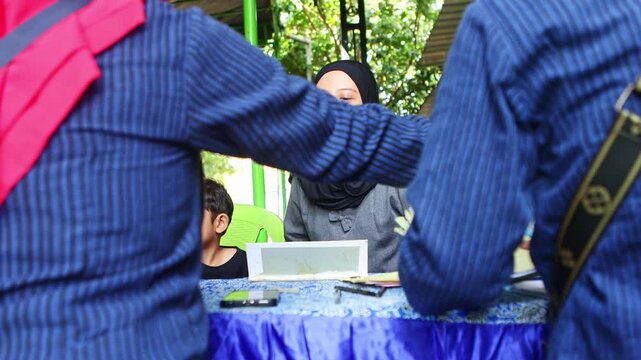 Muslim woman in hijab registering patientes at an outdoor clinic