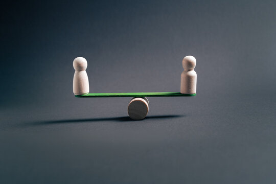 Business equilibrium concept with two wooden figures balancing on seesaw