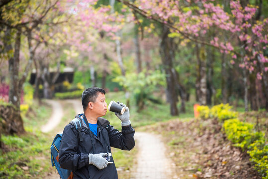 Asian man use professional digital camera take a photo. Smiling male photographer look at photo film camera outdoors. Mature adult man shooting photo in green nature park. Beautiful nature men hobby