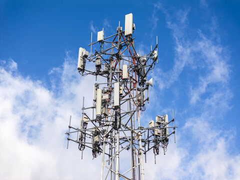 Aerial view of a cell phone tower reaching towards the heavens, its metallic structure contrasting against the vibrant blue sky and cotton-like clouds, Hollywood, Florida, United States.