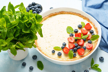 Tart with cheese and fresh berries on blue background.