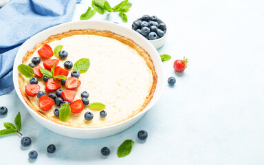 Tart with cheese and fresh berries on blue background.