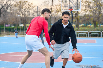 Fototapeta premium Young men playing street basketball on urban court