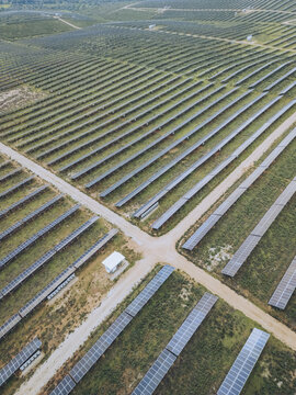 Aerial view of rows of solar panels stretch across the landscape, their surfaces reflecting the sunlight, creating a shimmering effect, Lagos, Faro District, Portugal.