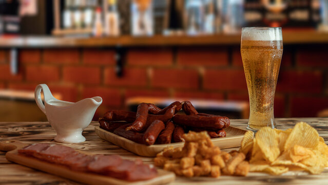 A nice evening in the pub with a glass of beer and snacks. Favorite sausages, crackers, chispa and delicious sauce. High quality photo