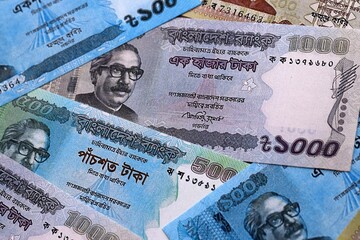 Fototapeta premium Bangladeshi taka money bills pile on table. Bangladesh banknotes of BDT currency close up.