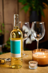 Obraz premium Bottle of white wine, two empty wine glasses and burning candles on table in cozy home interior. Concept of romantic dinner, date night and drinking wine