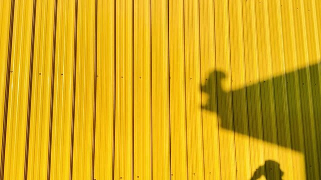 Bright yellow corrugated metal roof panels form bold vertical lines beneath a deep blue sky. Minimalist architectural background with vivid contrast, clean geometry, and strong industrial texture.