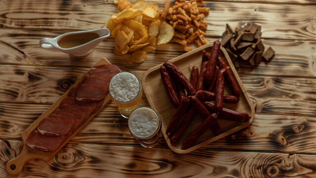 A nice evening in the pub with a glass of beer and snacks. Favorite sausages, crackers, chispa and delicious sauce. High quality photo
