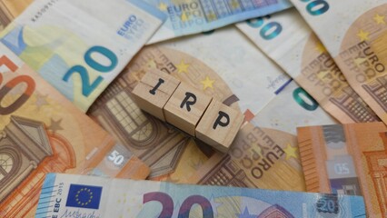 Obraz premium IRP acronym made of wooden letter cubes on pile of Euro banknotes. Individuele Pensioen Spaar (Individual Pension Savings)
