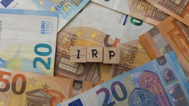 IRP acronym made of wooden letter cubes on pile of Euro banknotes. Individuele Pensioen Spaar (Individual Pension Savings)
