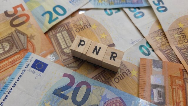 PNR acronym made of wooden letter cubes on pile of Euro banknotes. Plan National de Reprise (National Recovery Plan)