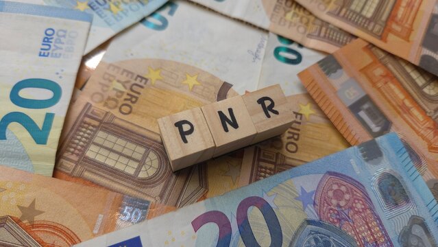 PNR acronym made of wooden letter cubes on pile of Euro banknotes. Plan National de Reprise (National Recovery Plan)