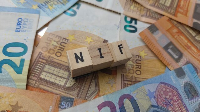 NIF acronym made of wooden letter cubes on pile of Euro banknotes. Num&eacute;ro d'Identification Fiscale (Tax Identification Number)