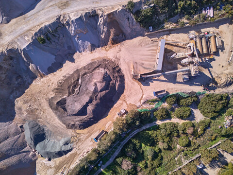 Aerial view of a quarry's stark geometry, where raw earth meets industrial precision, a contrast of textures under the sun, Manilva, Andalusia, Spain.