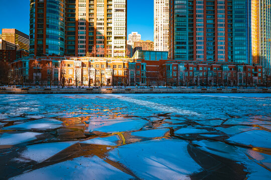 Impressive and beautiful view of apartment buildings rising along the frozen Chicago River, with ice chunks floating downstream, Chicago, IL, USA