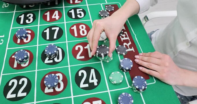 Player stacks casino chips on roulette layout tapping number squares. Hand moves tokens building bet position while table grid shows odds clearly