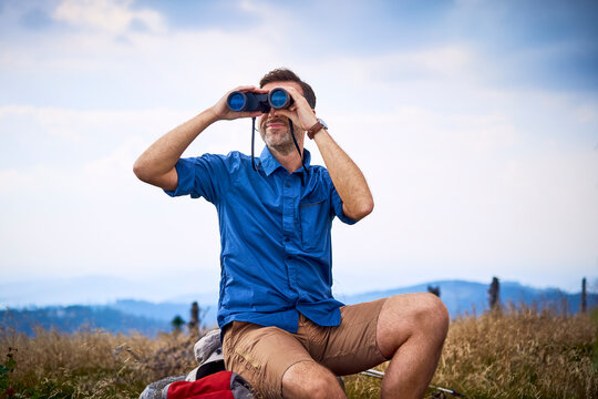Man looking through binoculars during hiking trip