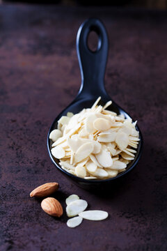 Spoon of sliced and blanched almonds on rusty ground