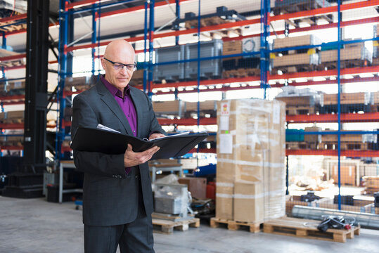 Businessman with documents on factory shop floor